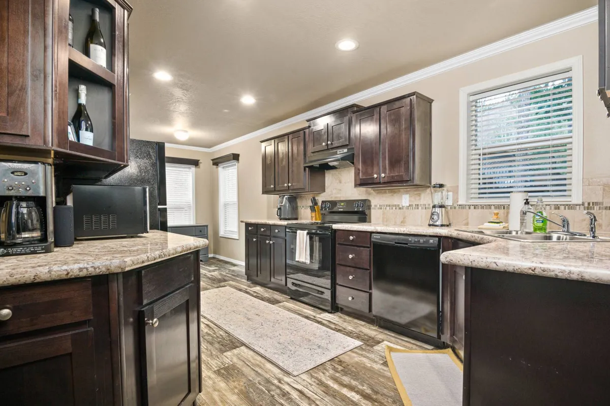 A stylish kitchen with a prominent island, dark cabinetry, stainless steel appliances, and plenty of counter space is showcased. Natural window light floods the area, making it feel bright and inviting—the perfect backdrop for cooking or entertaining.
